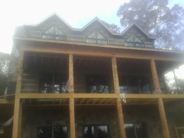 Dormers and porch framing on a large log home under construction — Roof Coating work by our crew in Orange Lake
