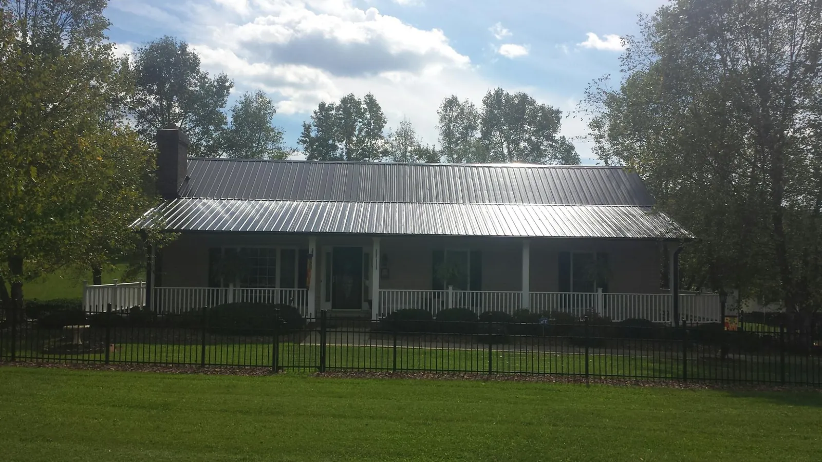 Gray metal roof on a brick ranch with a full width front porch — Gutter Guard Installation work by our crew in Orange Lake