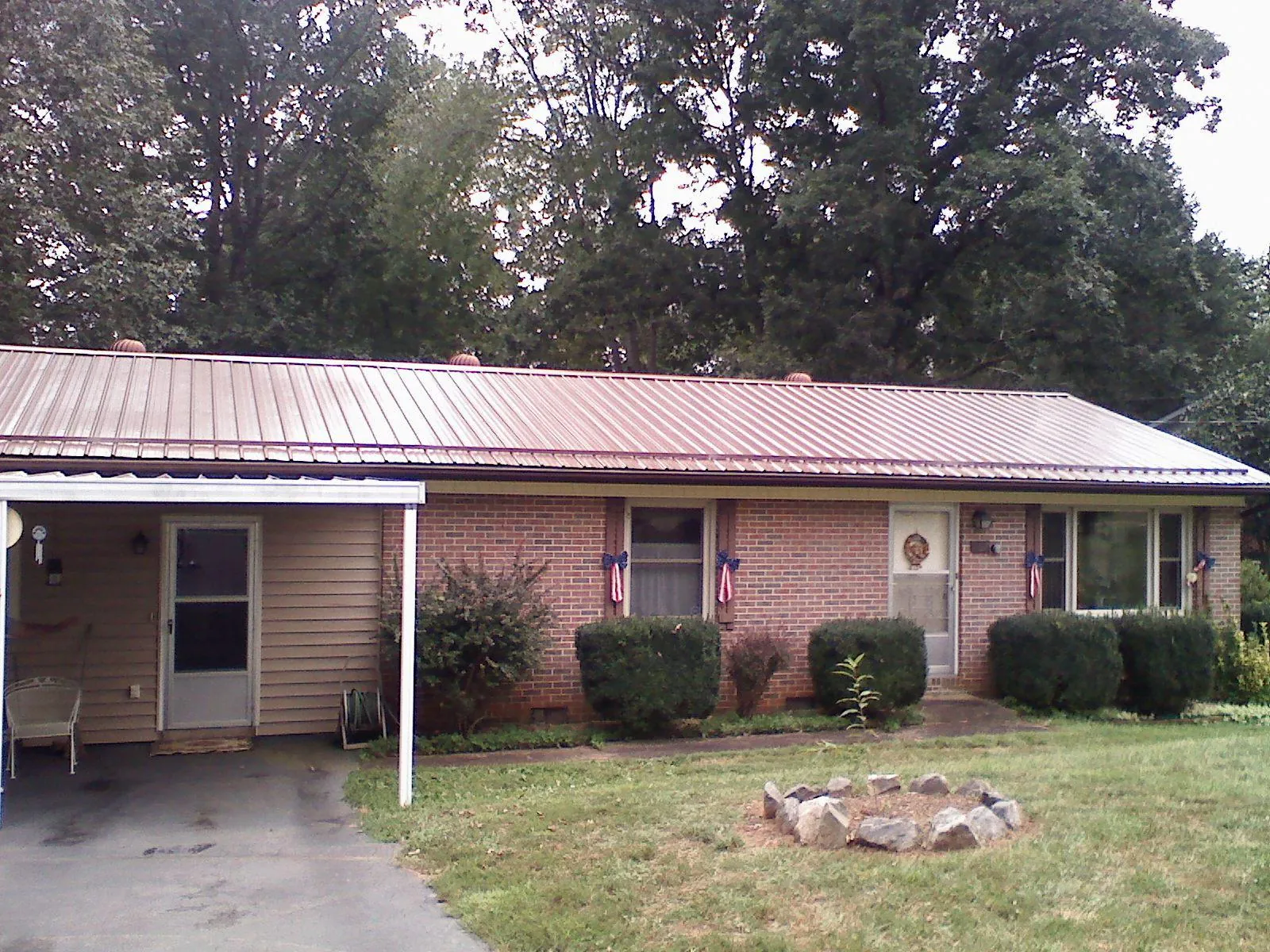 Bronze metal roof and carport on a brick ranch home — Roof Repair work by our crew in Orange Lake