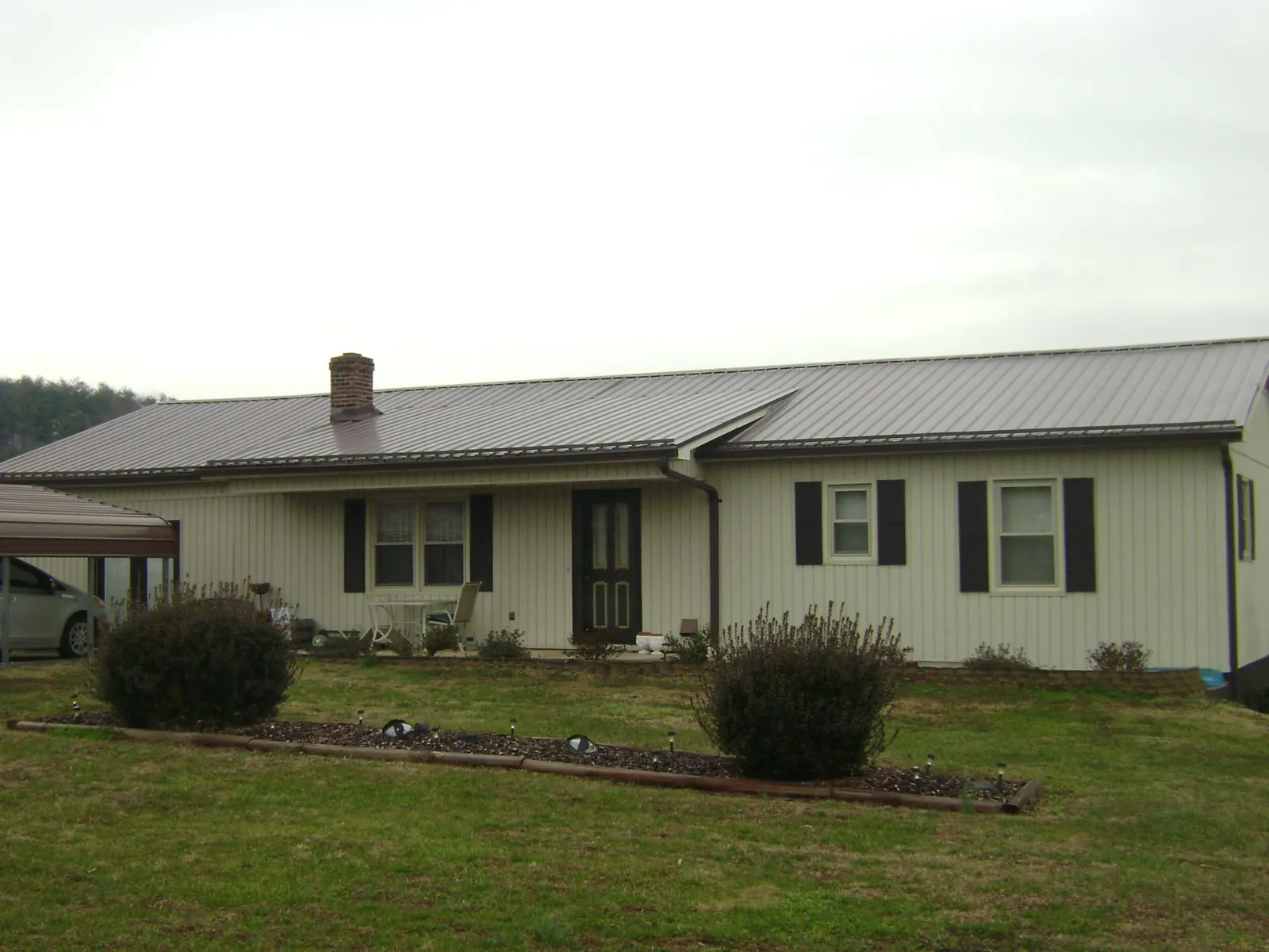 Brown metal roof on a cream sided ranch home with a brick chimney in Orange Lake