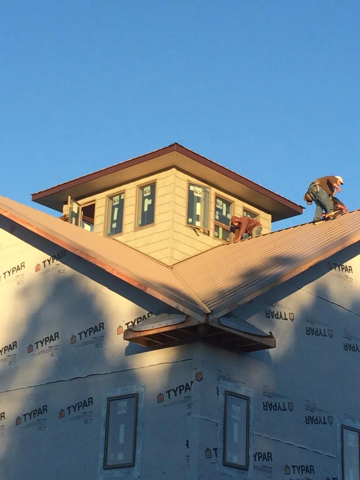 Roofers working around a rooftop cupola on a new metal roof at sunset — Roof Waterproofing in Orange Lake by Roofing Brothers